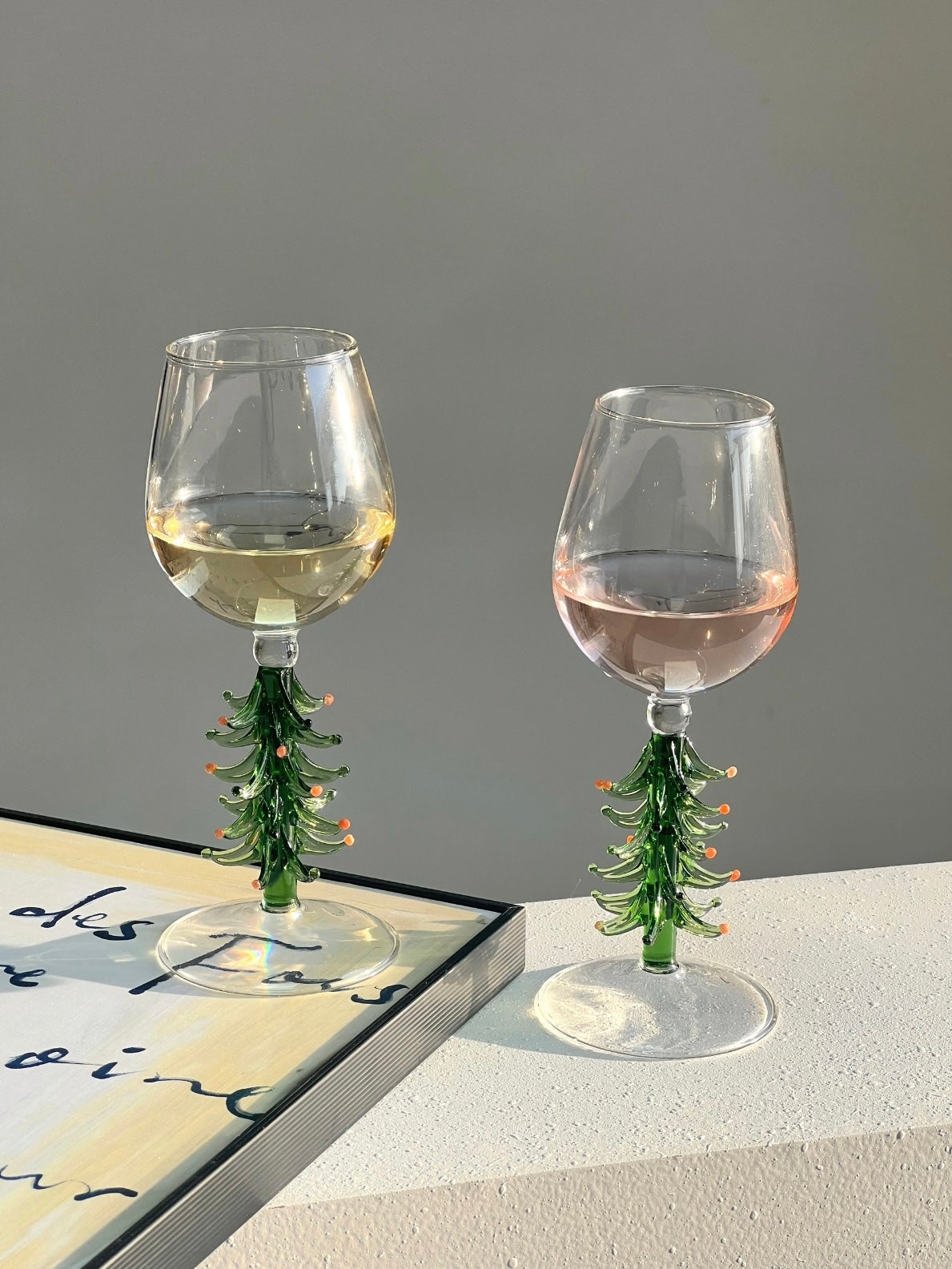 Holiday wine glasses with green Christmas tree stems styled over books