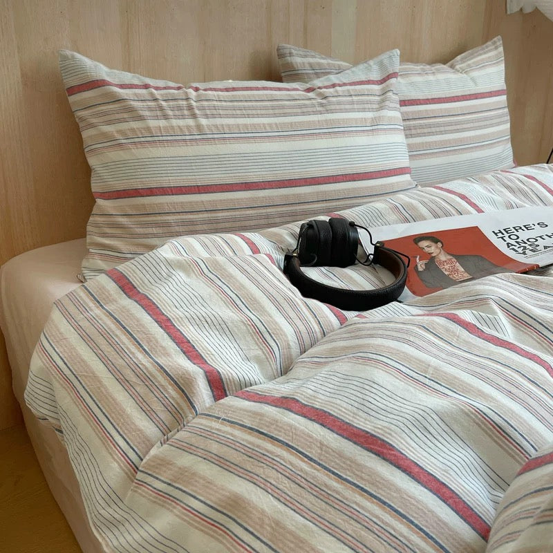 Striped bedding with a book and headphones on a bed in a bedroom setting.