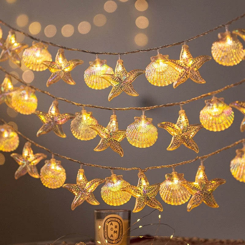 Decorative string lights with starfish and shell designs on a dark background
