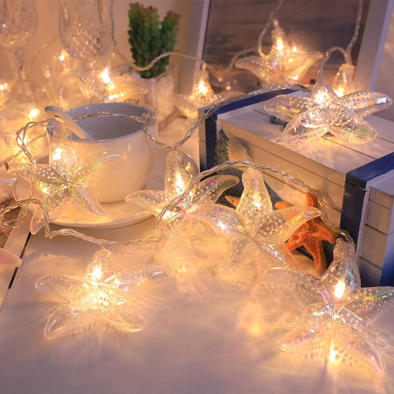 Butterfly-shaped string lights on a table with a teacup and books.