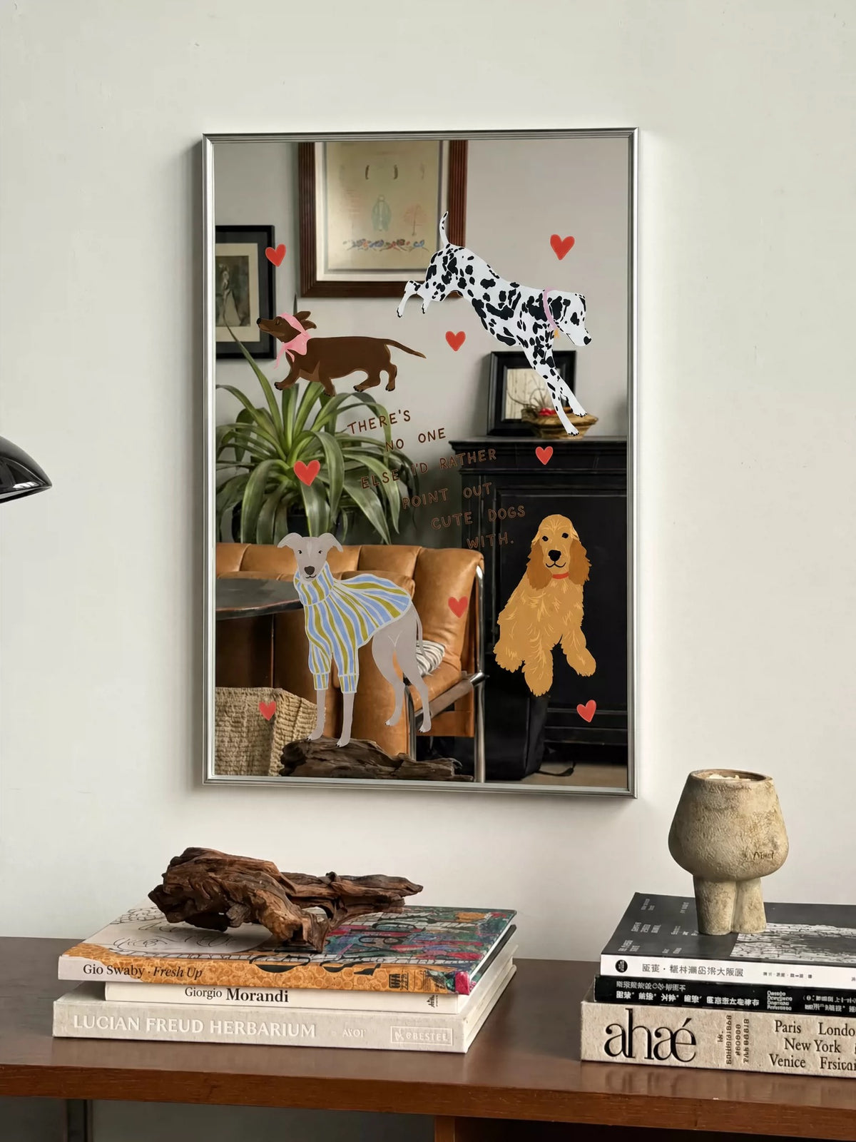 A colorful dog wall mirror hangs above a desk, with red hearts between the dog illustrations and reflected room.
