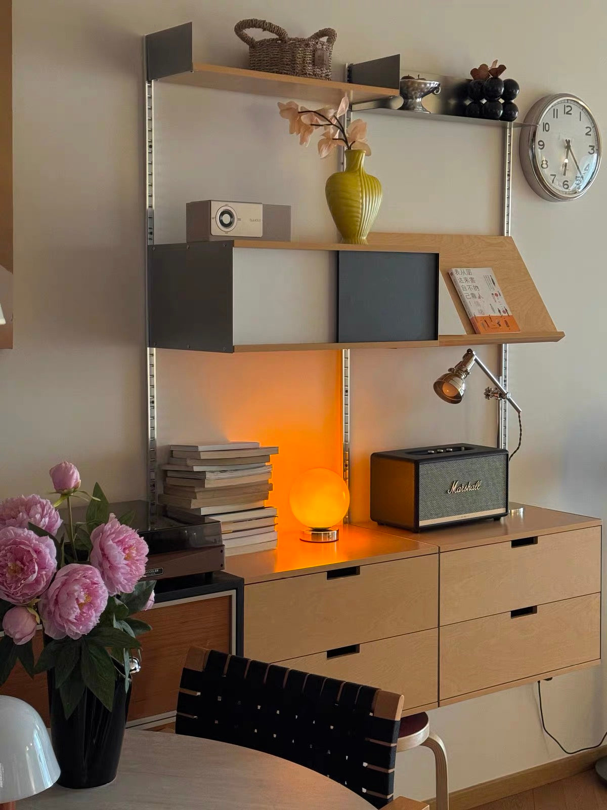 Modern bedroom with wooden dresser, shelves, and decorative items.