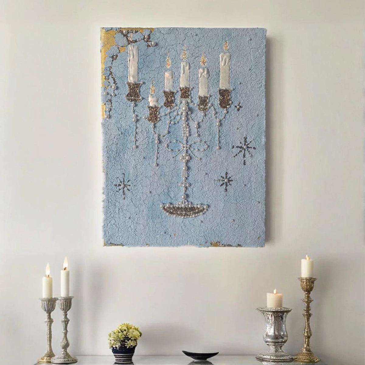 Blue candelabra wall art displayed above candles and small decorative objects