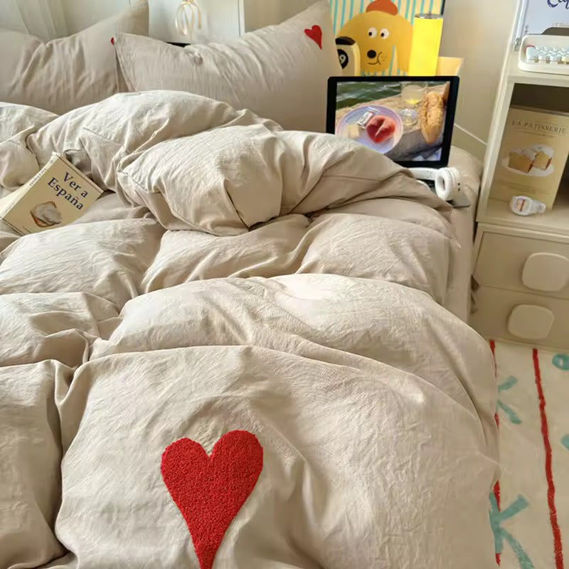 Embroidered red heart detail on the beige cotton duvet in romantic coquette style