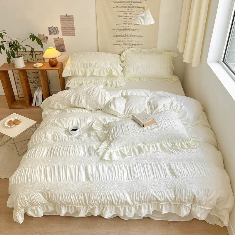 Neatly made bed with white ruffled bedding in a bright bedroom.