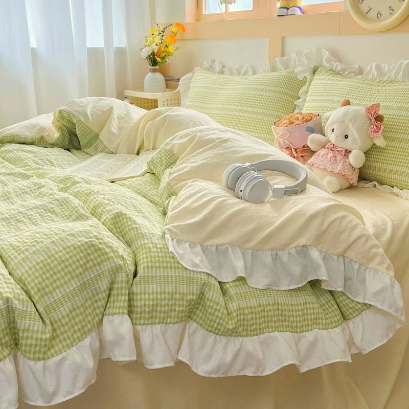 Green checkered bedding set with white ruffles on a bed, featuring a teddy bear and headphones.