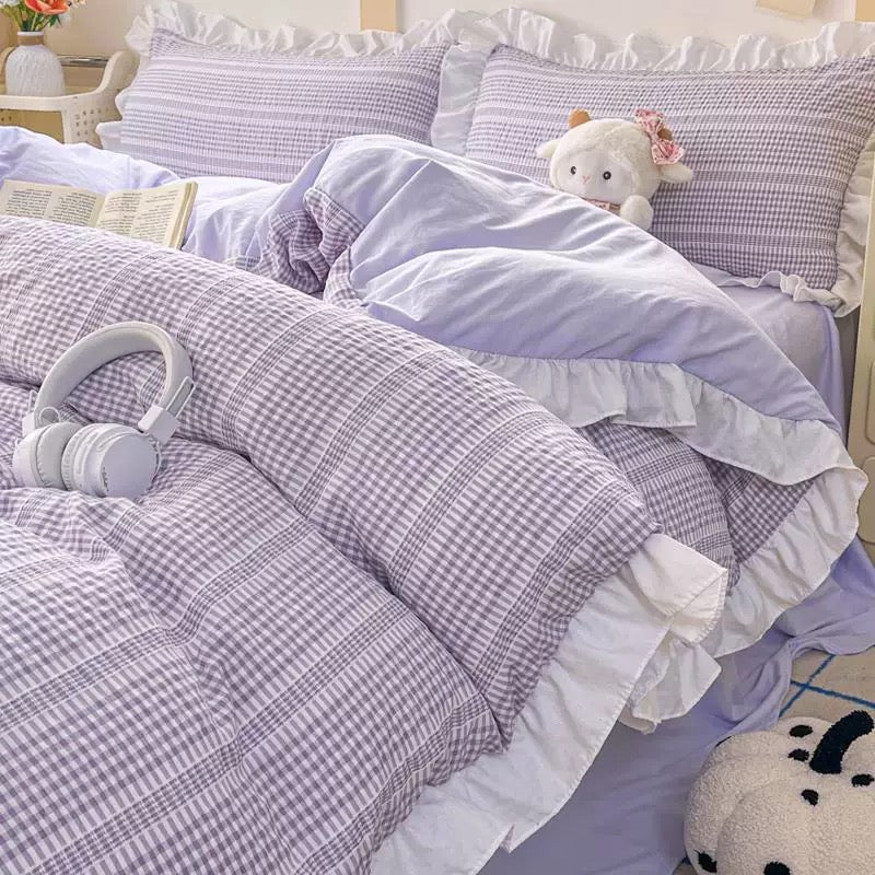 Bed with gray and white checkered comforter and pillows in a bedroom setting.