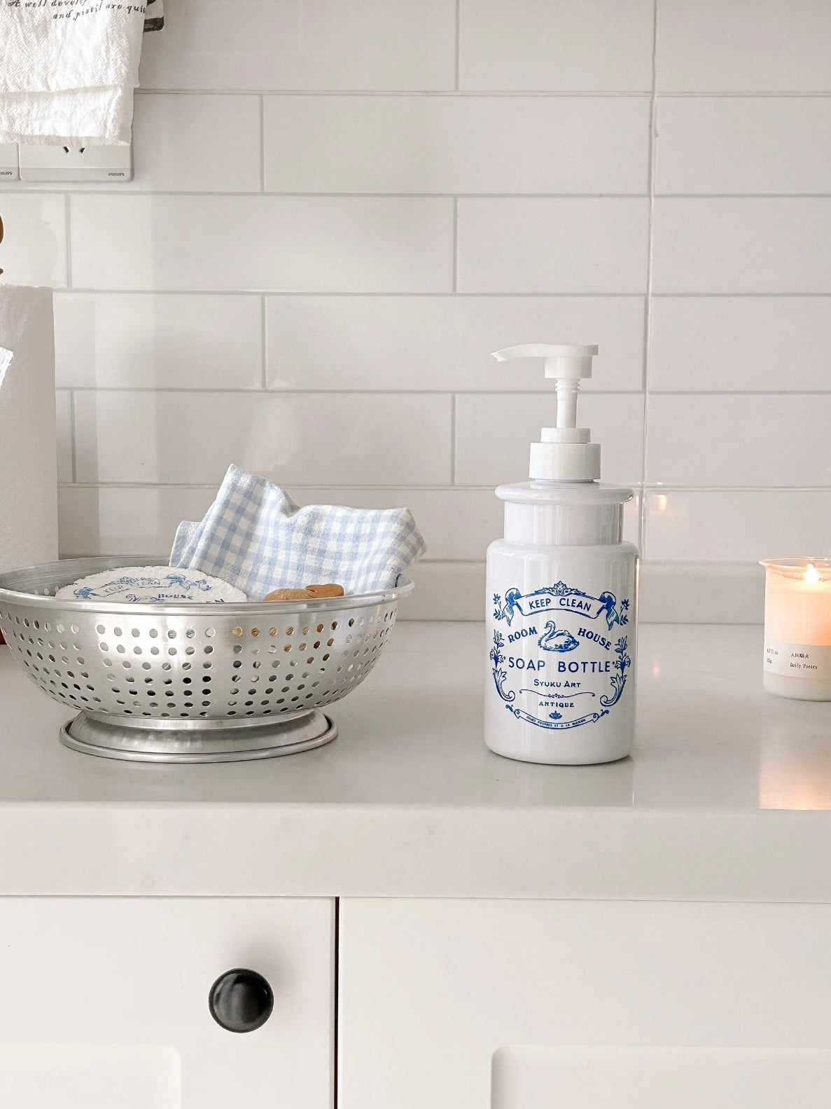 The Cottagecore soap dispenser stands upright on a white counter, with its blue swan artwork facing forward.