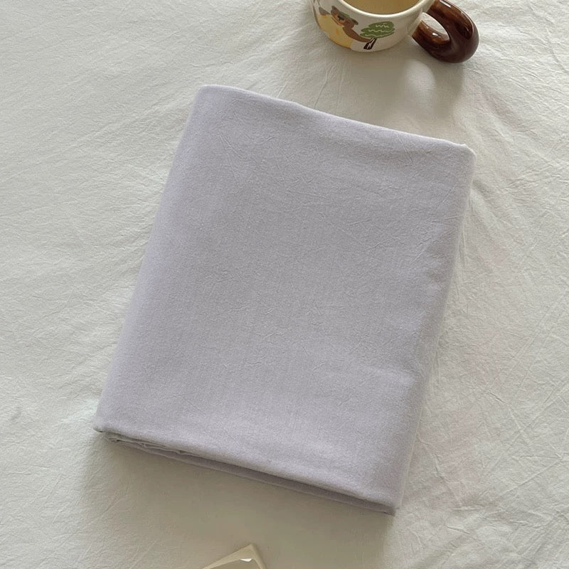 White folded towel on a textured white surface with a small cup in the background.