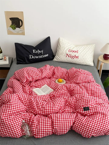 Red and white checkered comforter on a bed with pillows labeled 'Enjoy Downtime' and 'Good Night'.