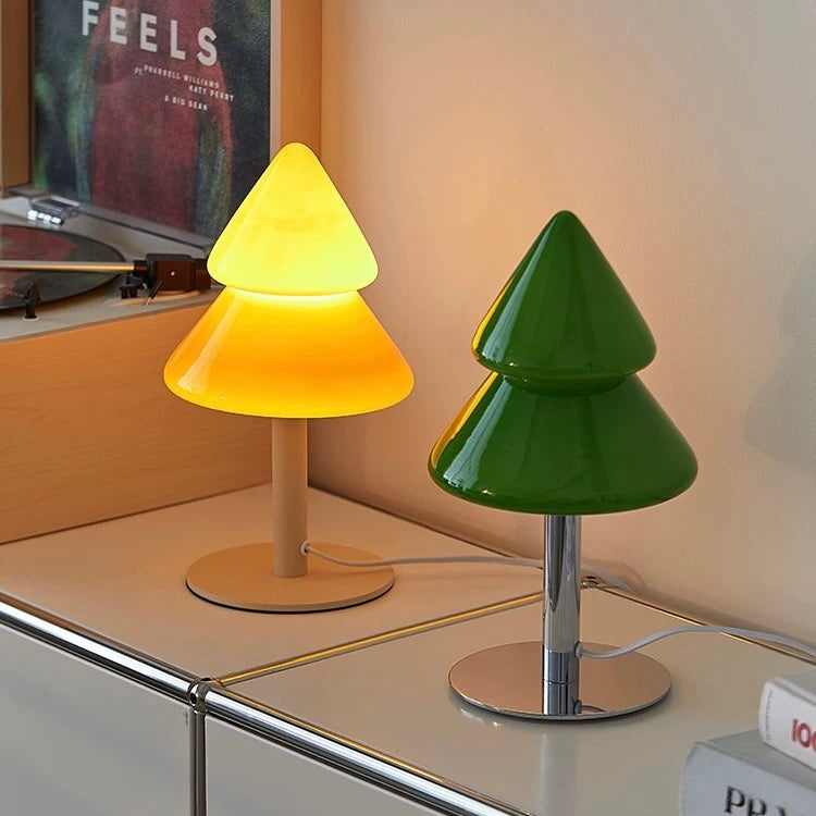 Two cone-shaped lamps, one yellow and one green, on a reflective surface with a blurred background.