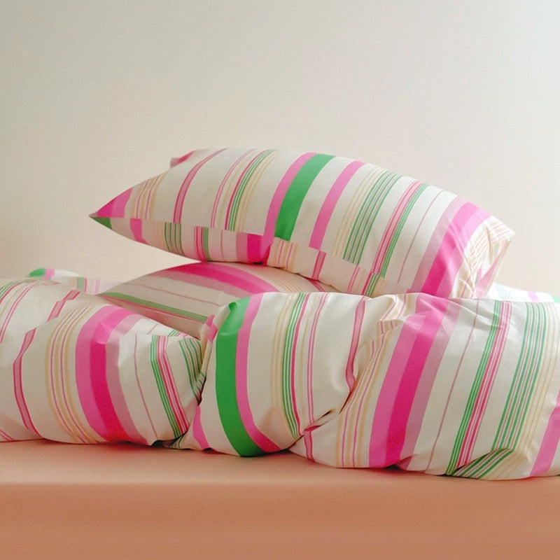 Striped pillows with pink, green, and white pattern on a beige background