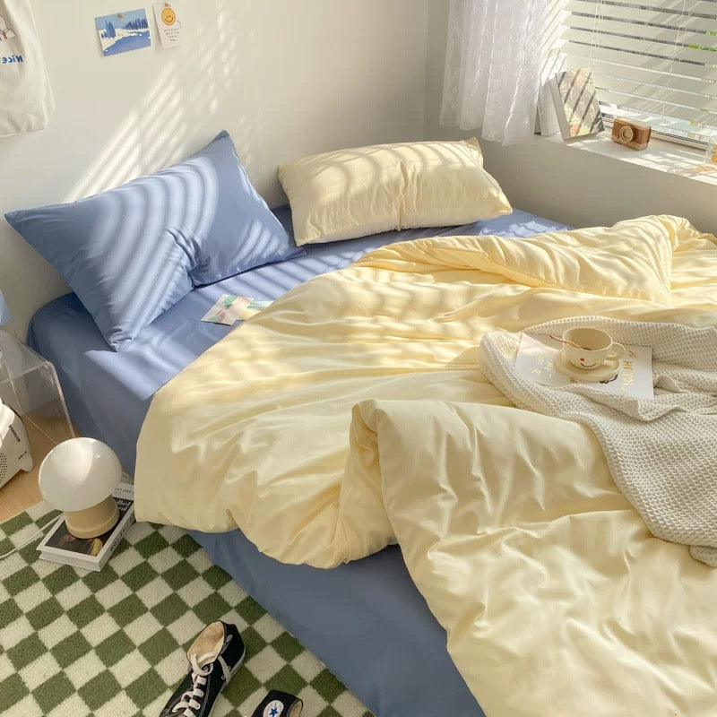 Minimalist pastel blue and cream bedding set styled in a cozy dorm room with sunlight.