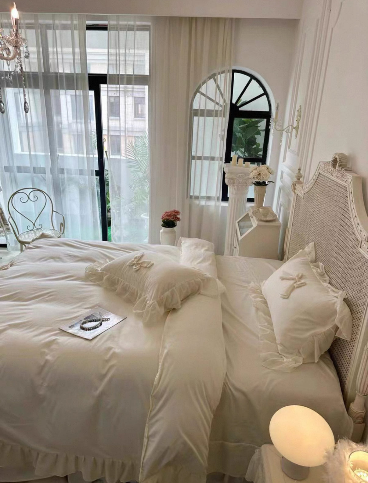 Neatly made bed in a bedroom with white bedding and decorative pillows.