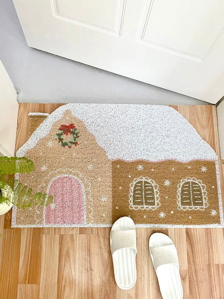 Cream Christmas door mat with gingerbread house design in a bright entryway