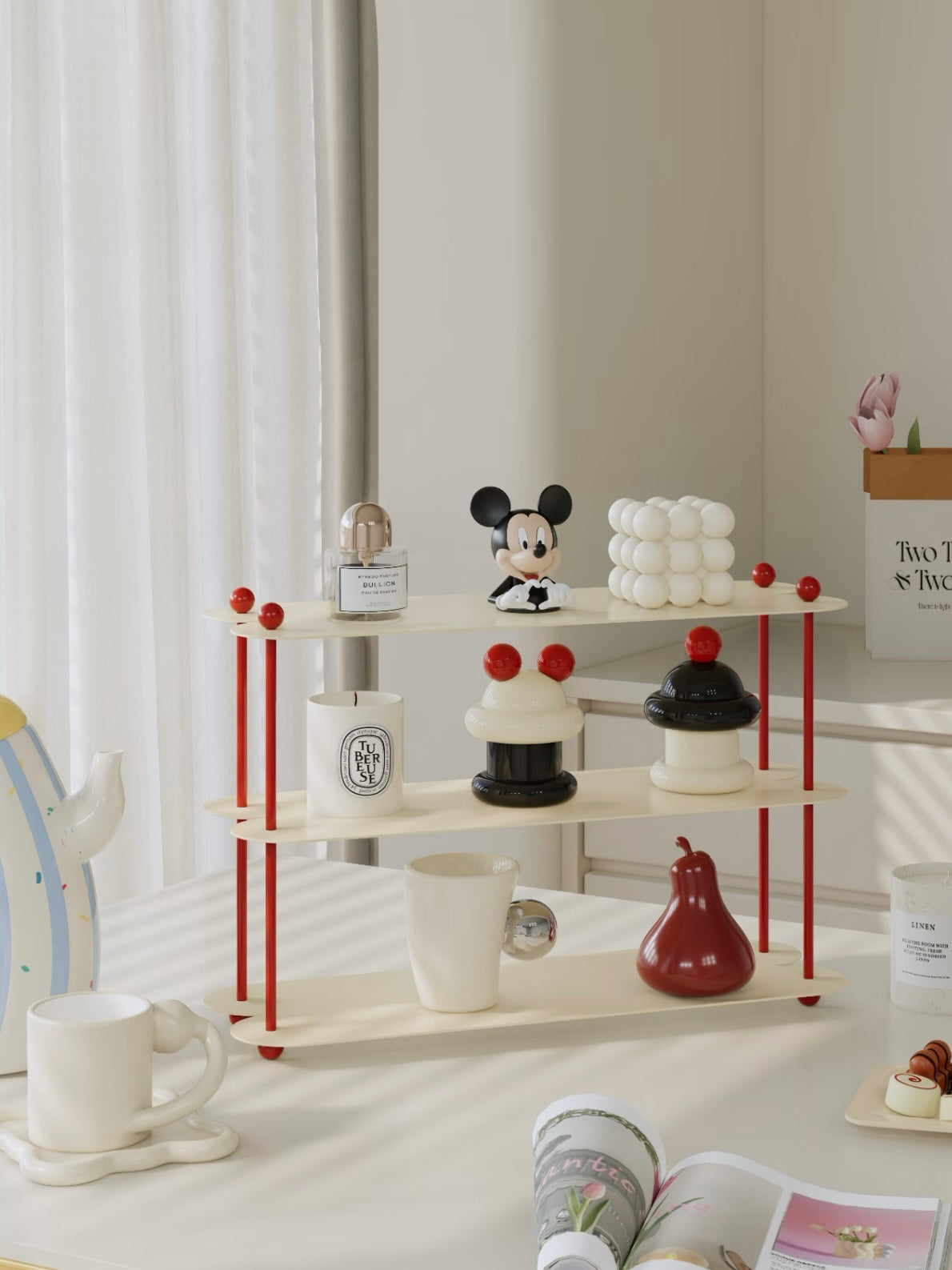 A cream iron shelf with red ball details is shown at an angle, displaying a mug, candles and small objects.