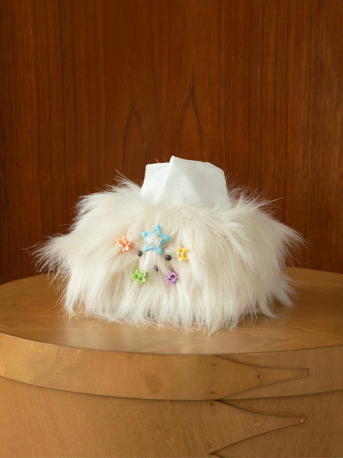 Cream White tissue cover with a dog face and colorful mini clips, standing on a wooden bedside table.