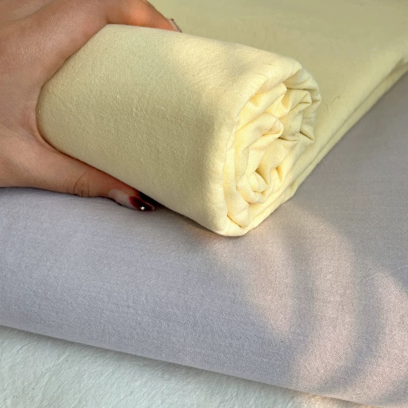 Rolled-up cream-colored fabric held by a hand on a light gray background