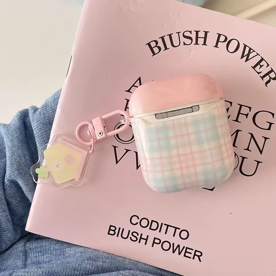 Pink and checkered airpod case with a keychain on a pink book titled 'BIUSH POWER'.