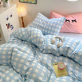 Bed styled with coquette pink pillow and pastel blue plaid duvet – cozy and Pinterest-worthy setup