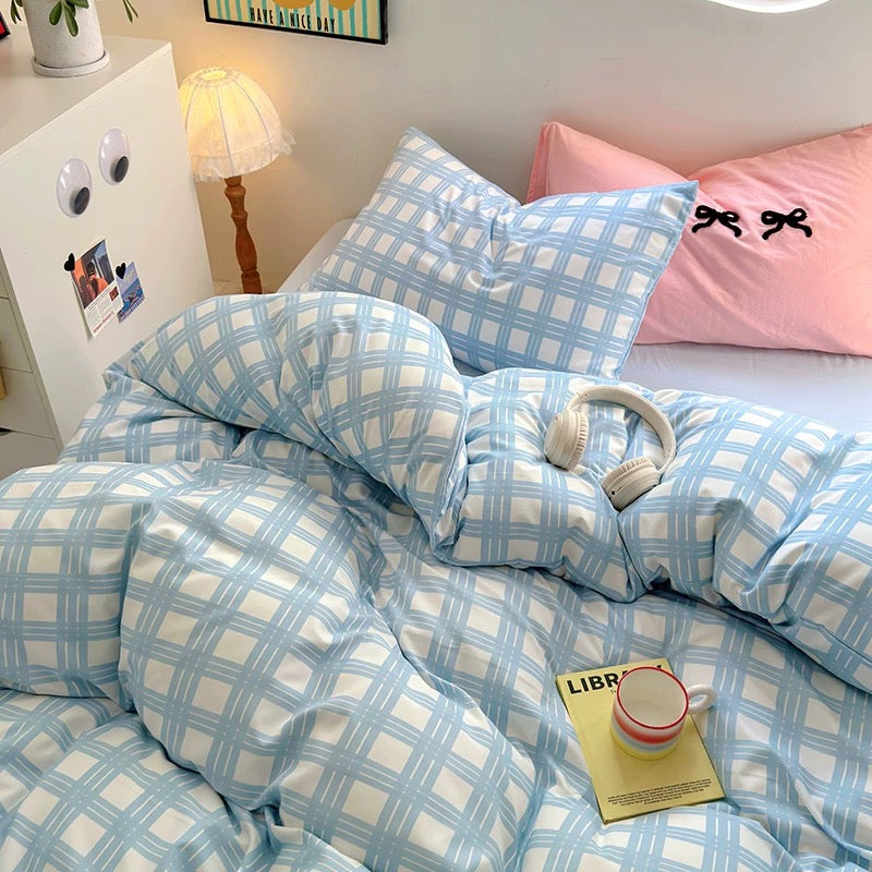Bed styled with coquette pink pillow and pastel blue plaid duvet – cozy and Pinterest-worthy setup