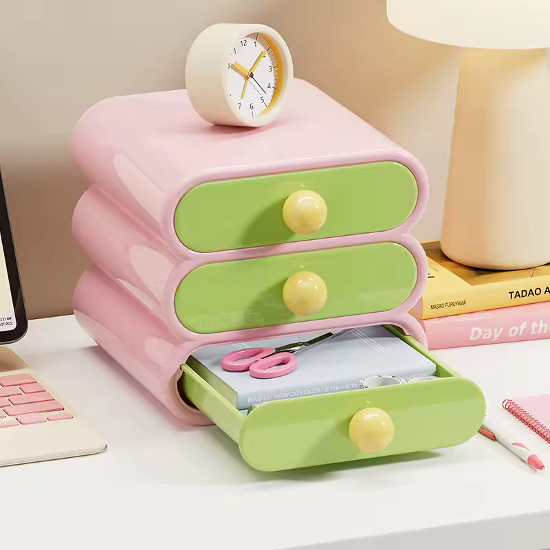 Pink and green desk organizer with open drawer on a desk.