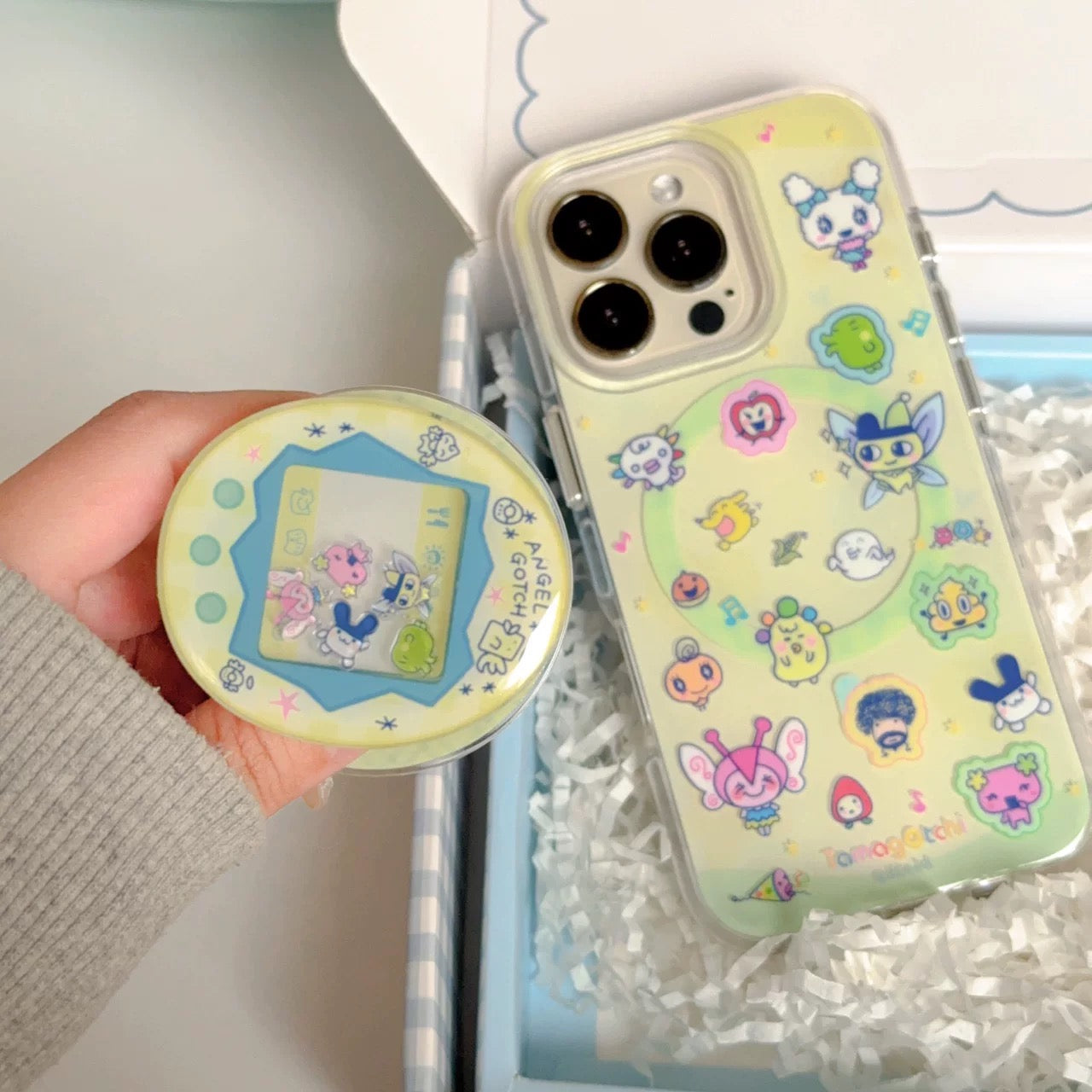 Phone case with cartoon designs held by a hand, with a white background