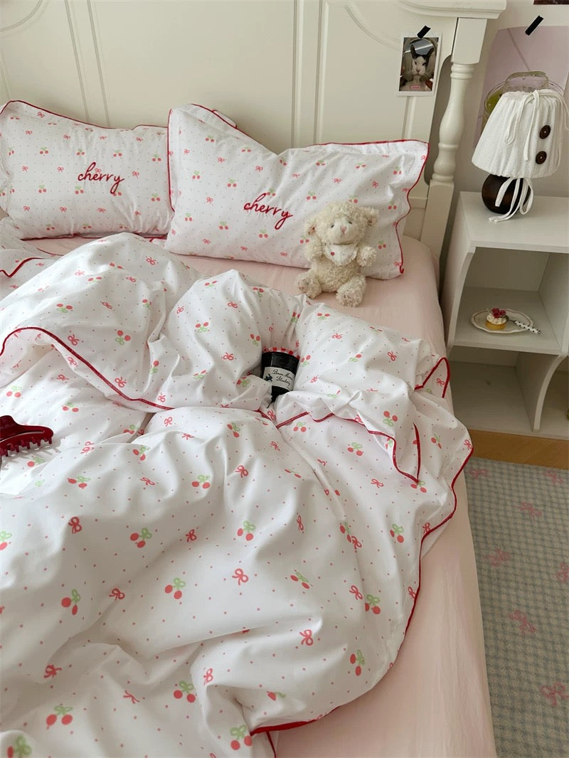 Bedding set with cherry pattern on a bed in a bedroom setting.