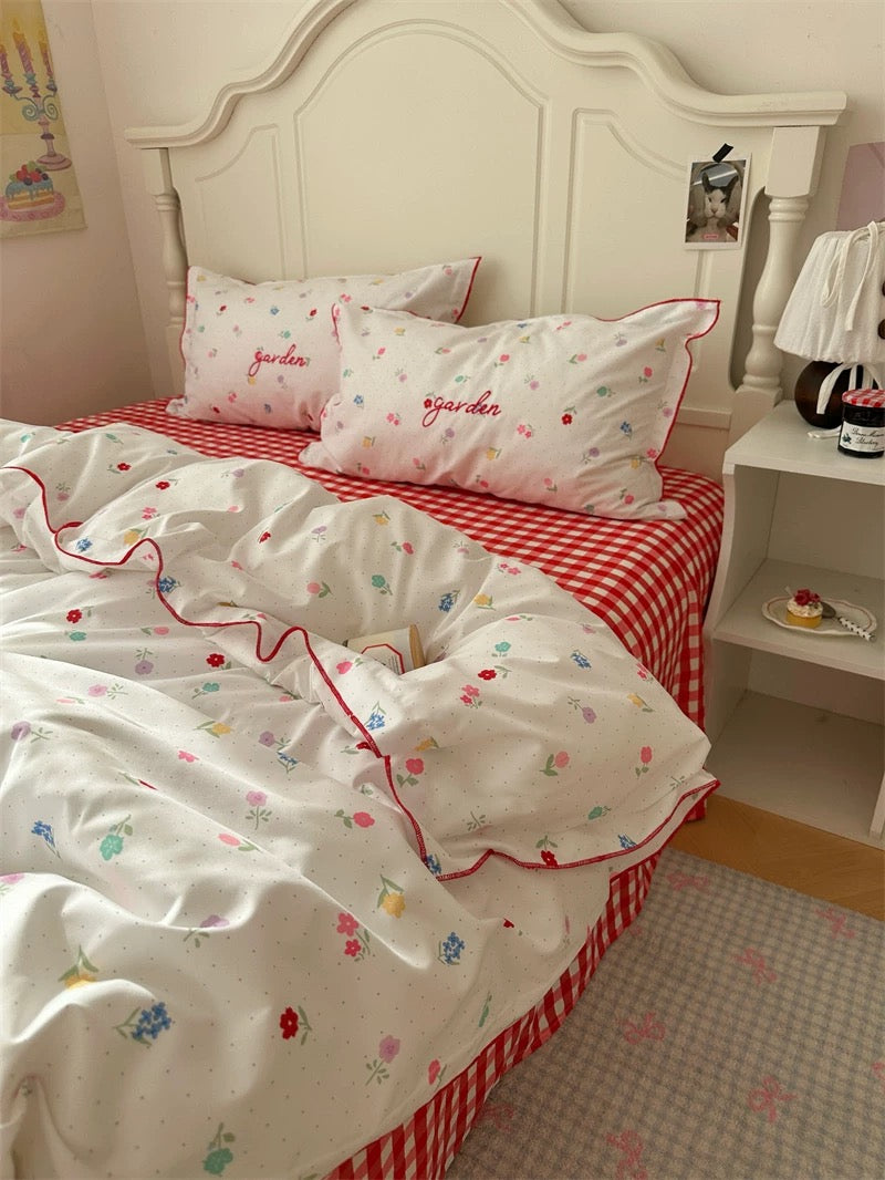 Bed with red and white checkered bedspread and floral patterns, in a room setting.