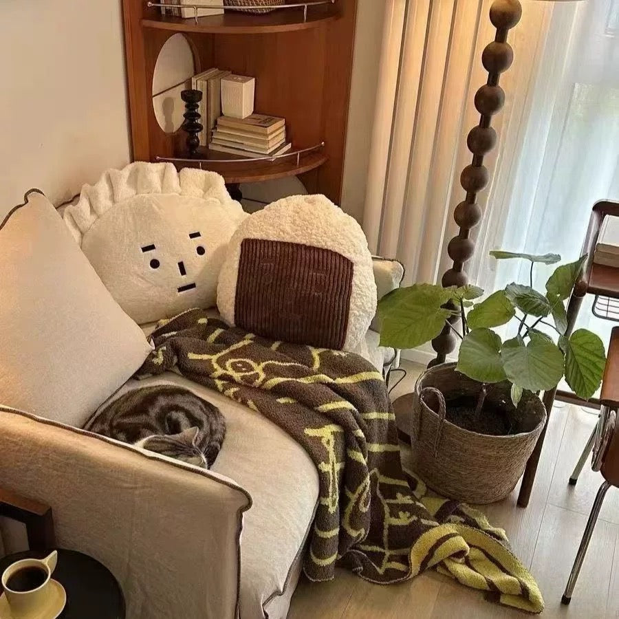 Cozy living room with a beige armchair, patterned blanket, and cat sleeping on it.