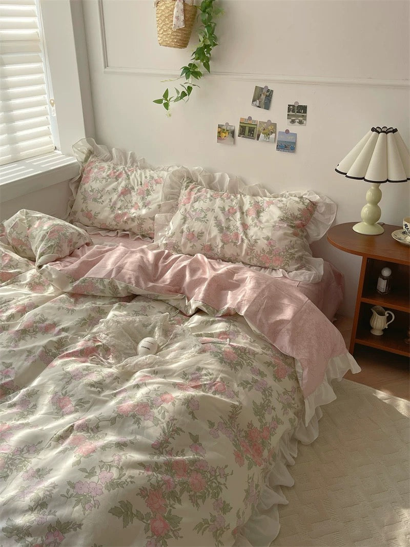 Floral bedding set on a bed in a bedroom with a lamp and window in the background.
