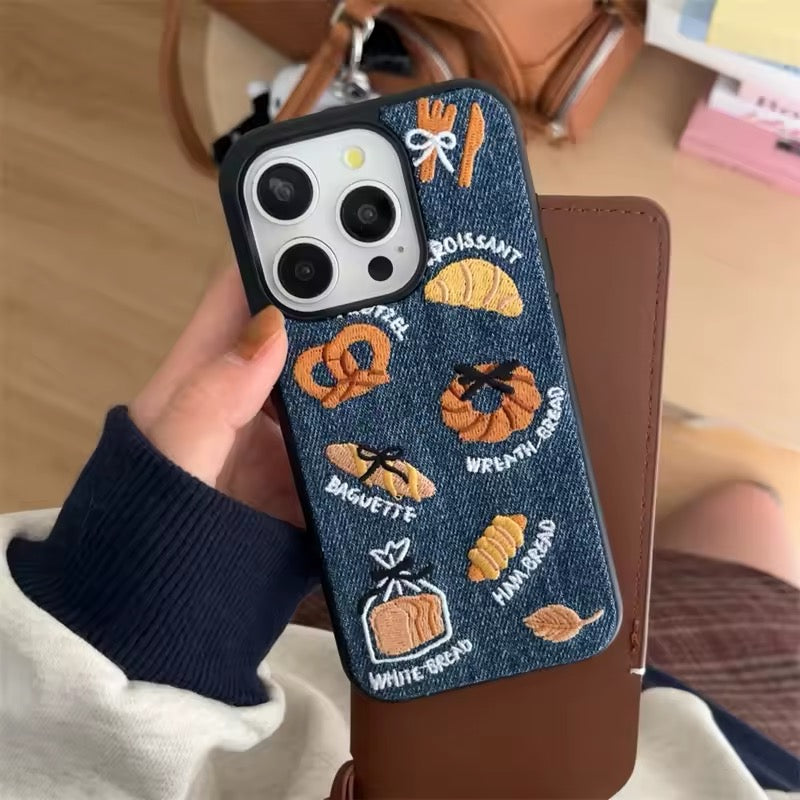 Close-up of embroidered bread icons on denim case
