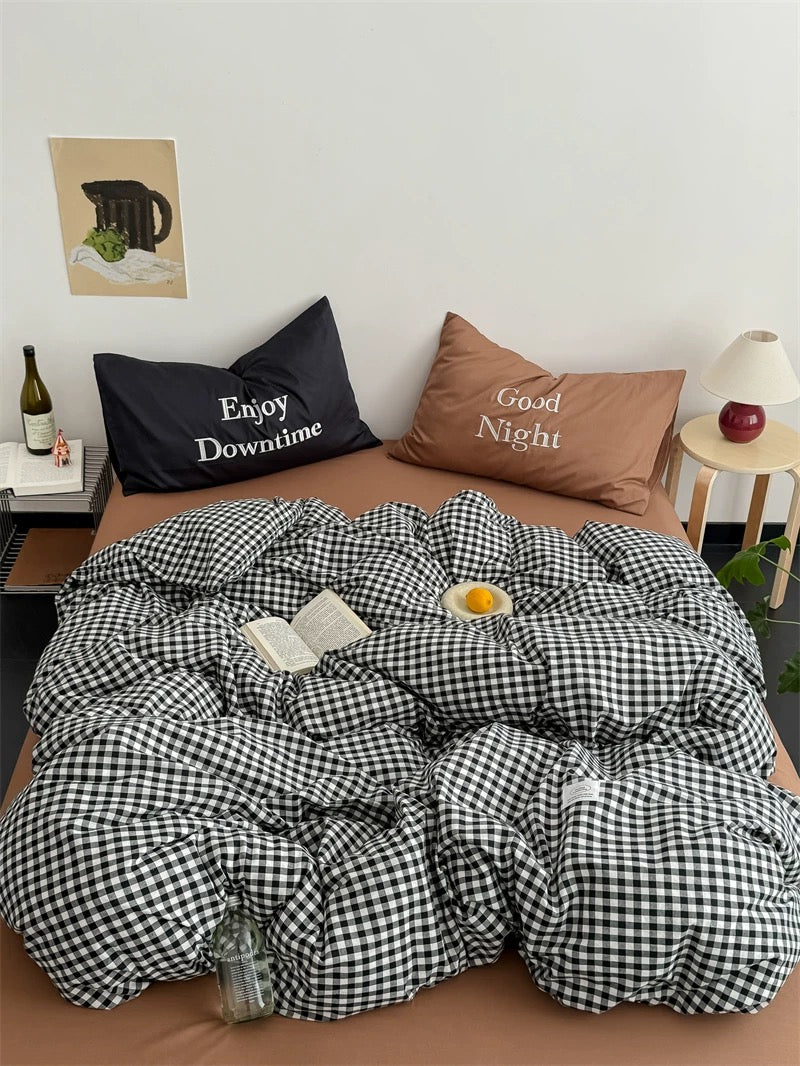 Checkered duvet cover on a bed with pillows and a small table in the background.