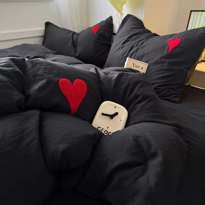 Overhead view of cozy red and black bedding with laptop and headphones