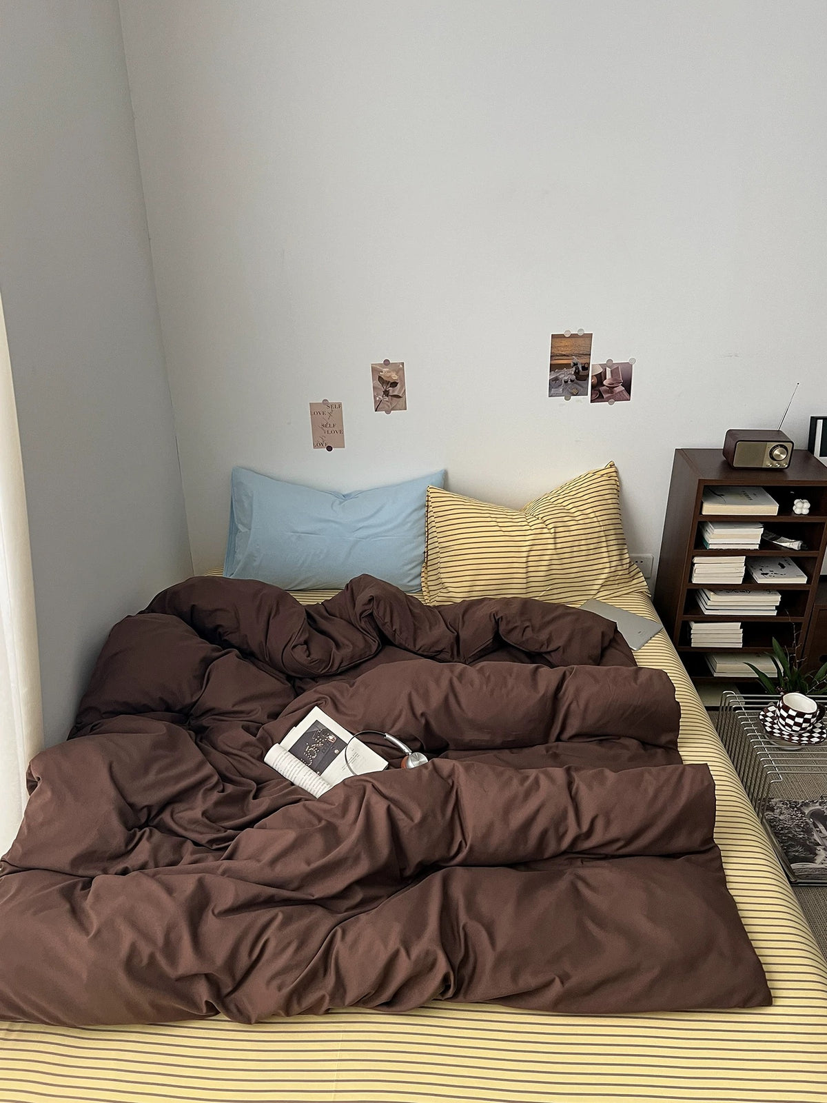 Dark brown bedding set styled on a bed with striped flat sheet and mixed pillowcases