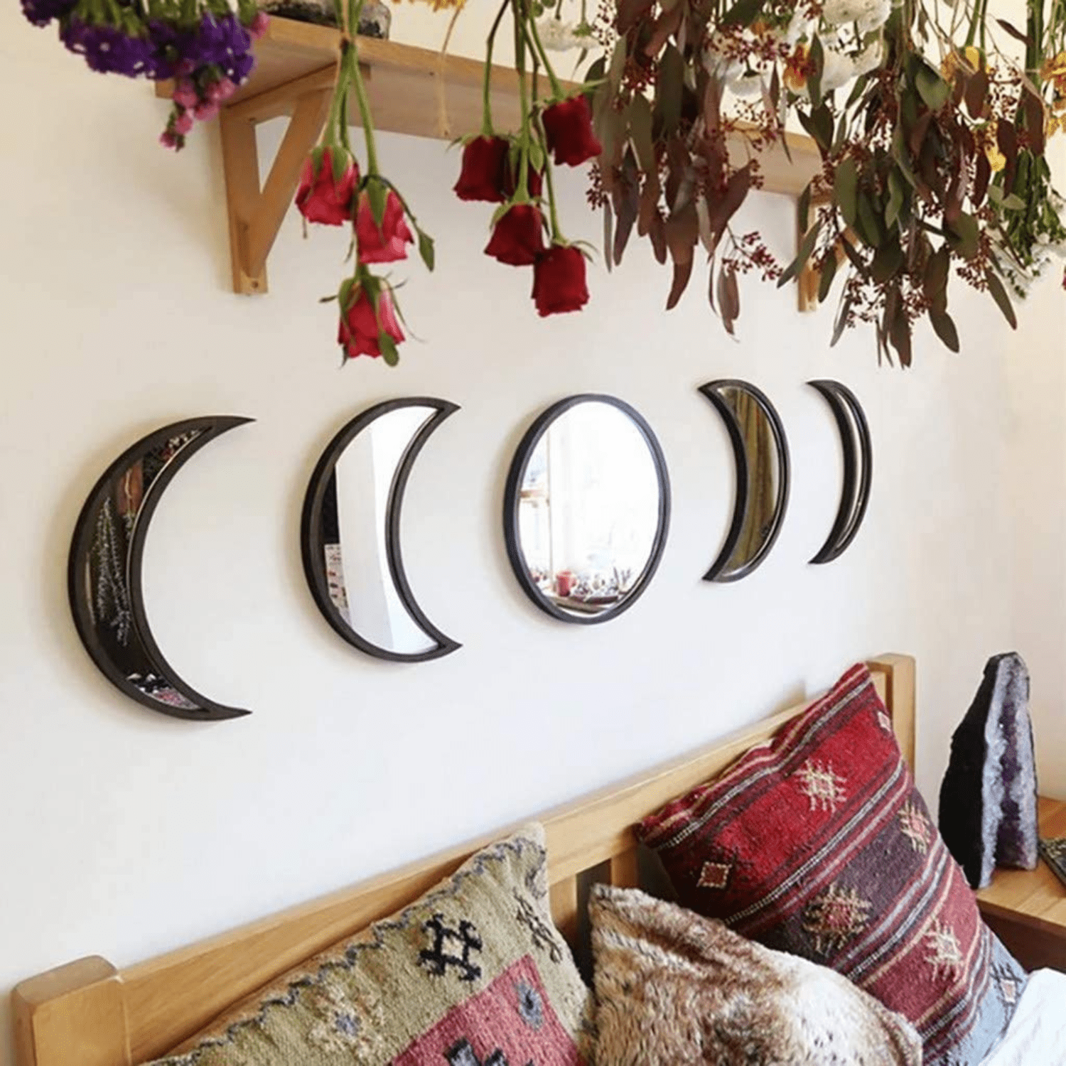 Black moon phase mirrors styled in a moody dark feminine bedroom