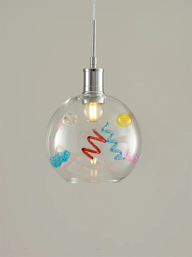Clear glass pendant light with colorful decorations on a neutral background