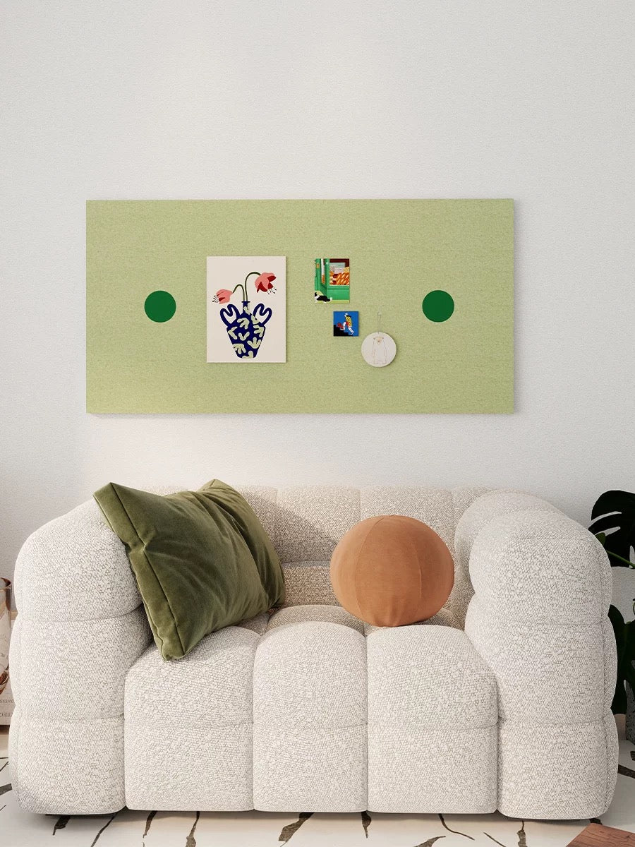 Decorative green pin board with circular accents and postcards on a living room wall.