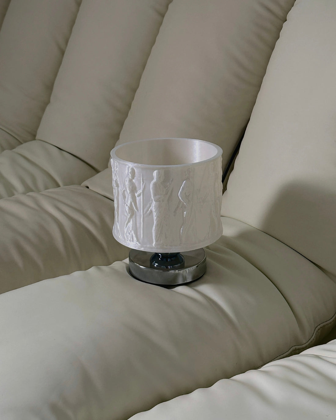 Table lamp with a textured white shade on a wooden base against a window blind background