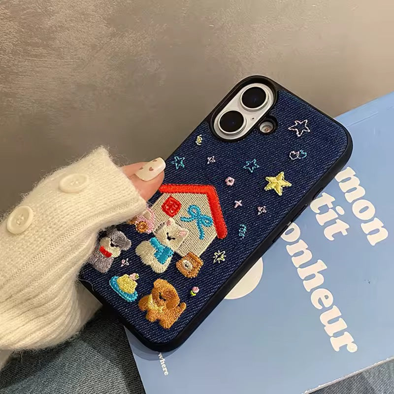 Phone case with embroidered designs held by a person wearing a white sweater.