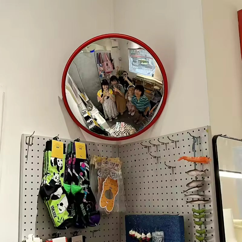 Round mirror with red frame on a pegboard with various items