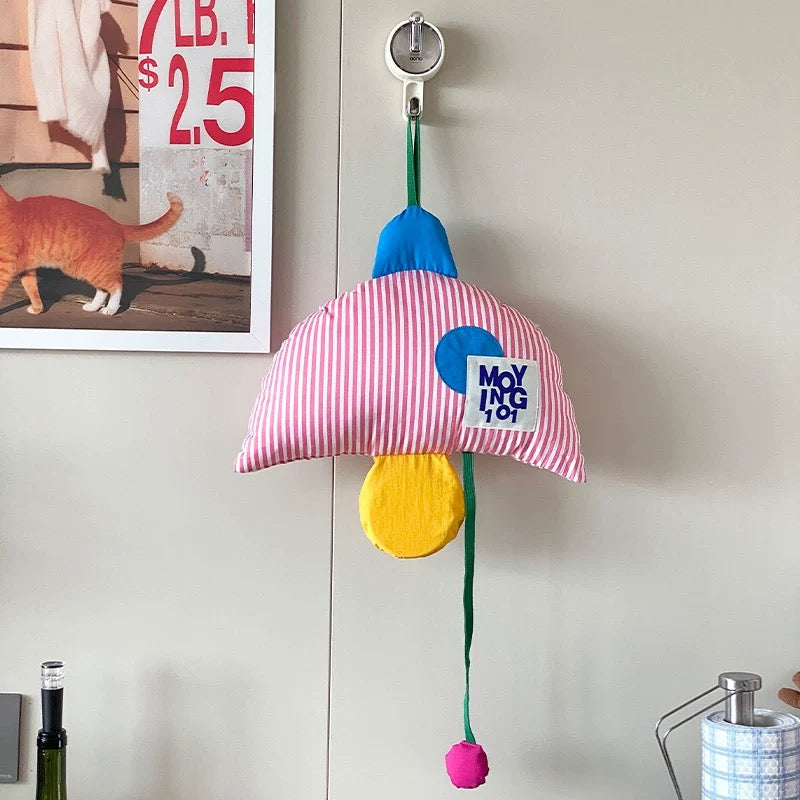 Colorful cat toy with striped pink umbrella and blue and yellow accents hanging on a hook.