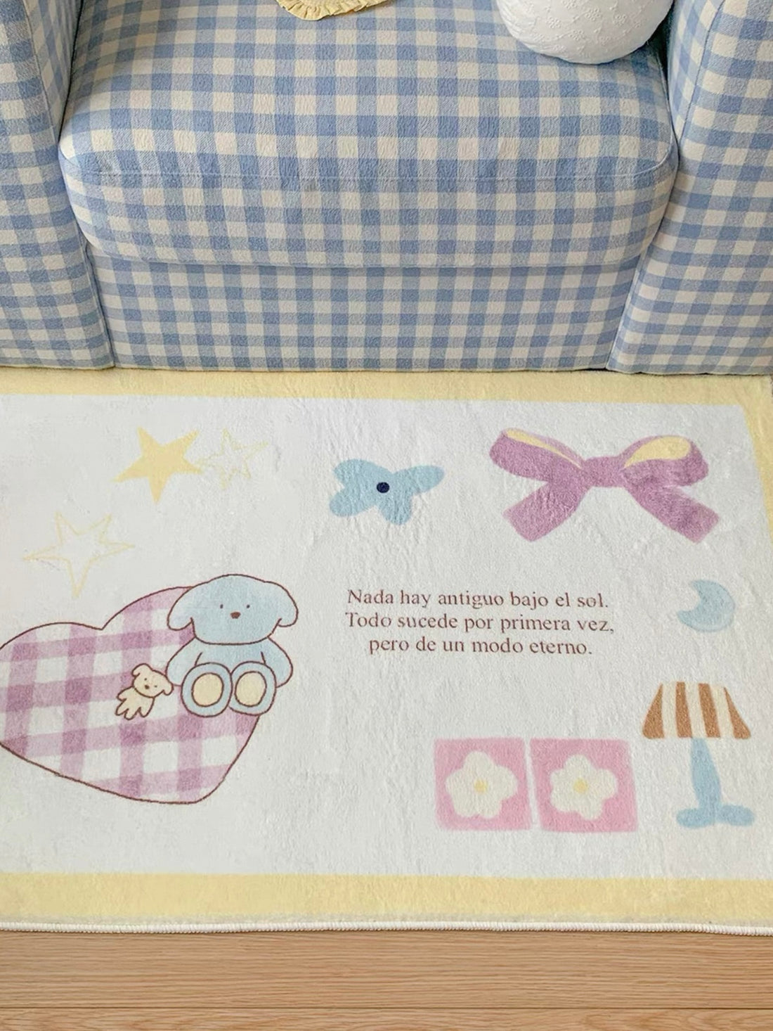 A blue bordered elephant rug shows an elephant holding a pink heart beside a house, stars and small patterned shapes.