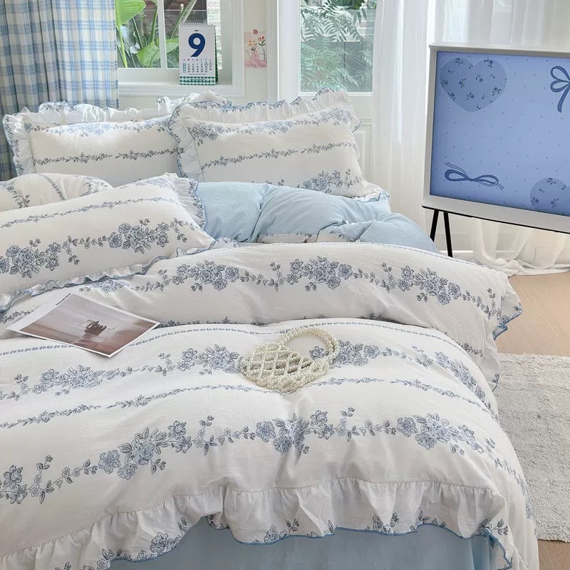 Floral patterned bedding set on a bed in a bright room with a calendar and TV in the background.