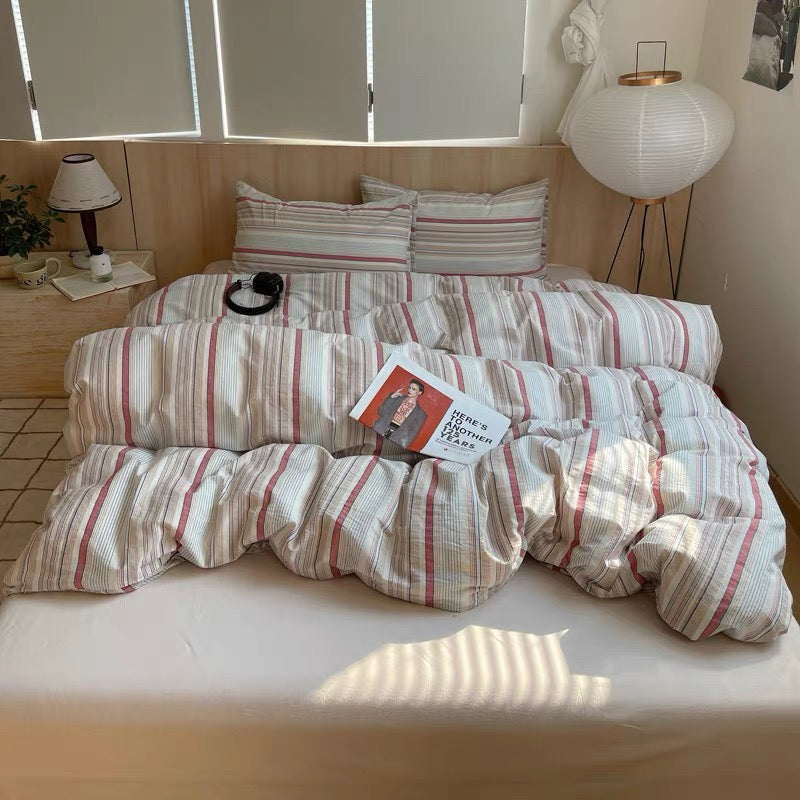 Bed with striped bedding and a magazine on a wooden nightstand in a room.