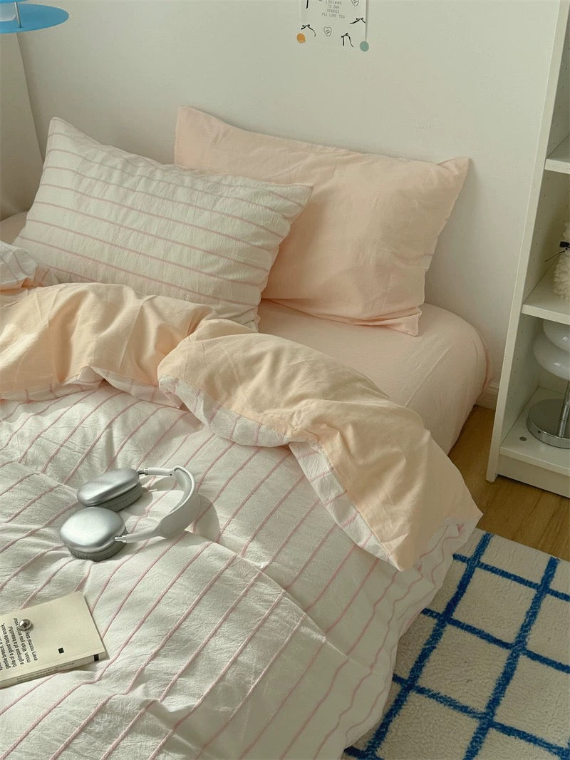 Bed with pink bedding and white pillows in a room setting.