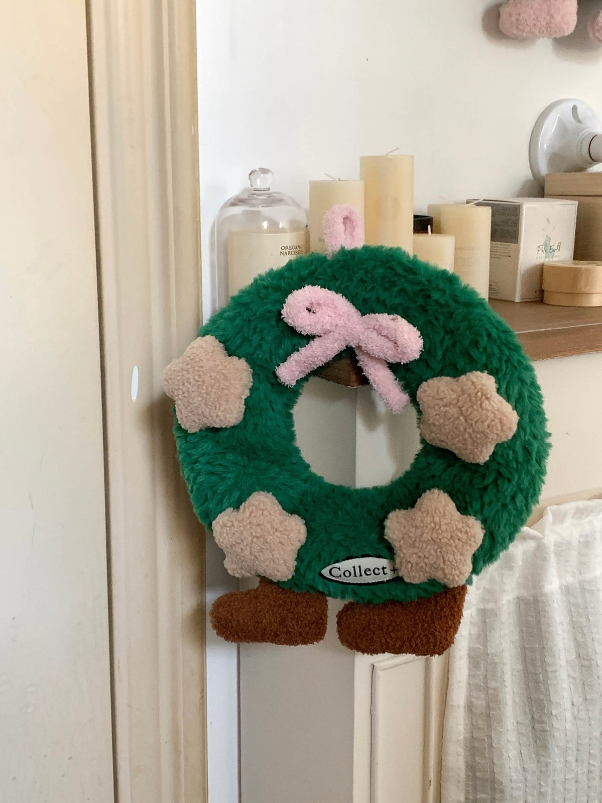 Fluffy Christmas wreath pillow with pink bow and plush stars resting on a chair