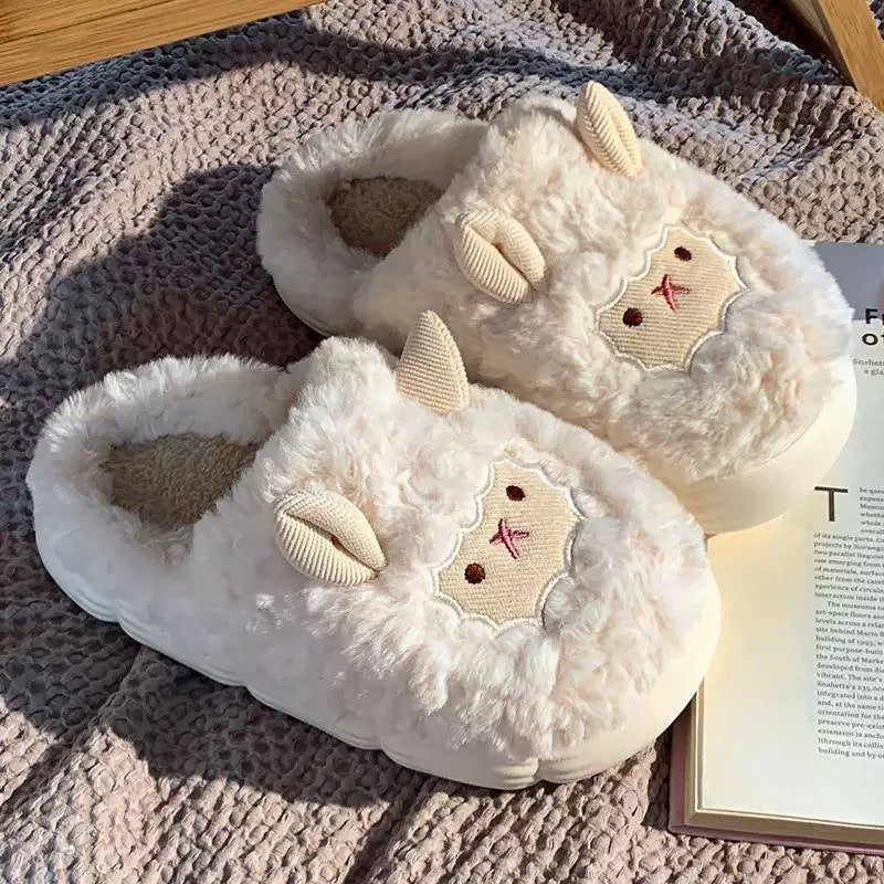 Pair of fluffy white slippers with lamb design on a textured surface.