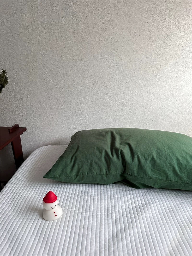 A forest green pillowcase has a plain surface with visible fabric folds.