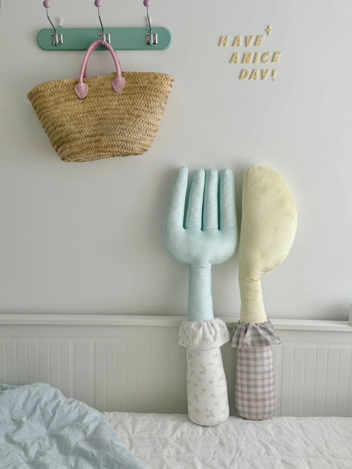 A blue fork pillow stands beside a yellow knife pillow, with pale patterned handles below their shaped heads.